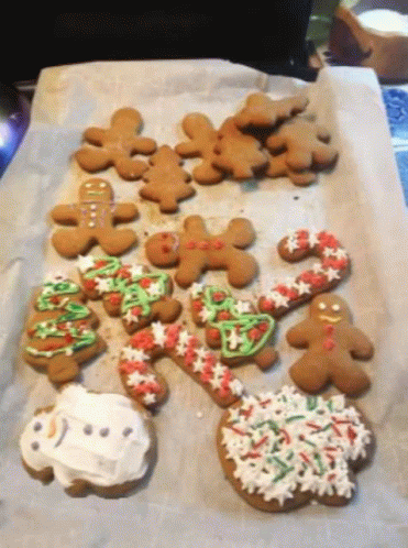A Bunch Of Gingerbread Cookies Are Sitting On A Tray GIF