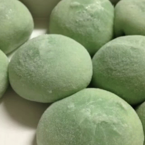 A Bunch Of Green Ice Cream Balls Are On A White Surface . GIF