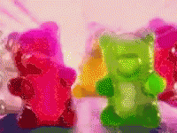 A Bunch Of Gummy Bears In Different Colors Are Sitting On A Table GIF