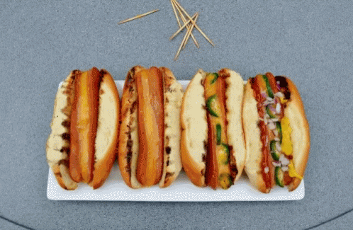 a bunch of hot dogs on a plate with toothpicks in the background