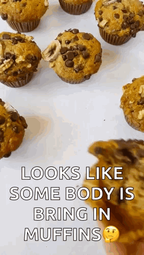 A Bunch Of Muffins Are Sitting On A Table And A Person Is Holding A Piece Of Chocolate Cake . GIF