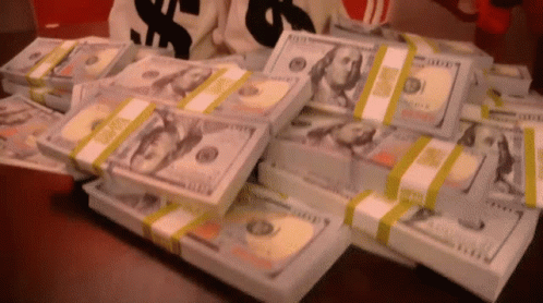 A Bunch Of Stacks Of Money On A Table GIF