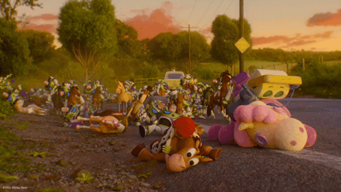 A Bunch Of Stuffed Animals Are Laying On The Side Of A Road GIF