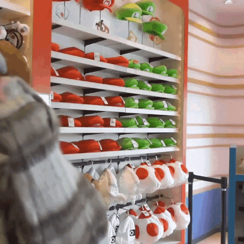 A Bunch Of Stuffed Mario Hats Are Hanging On A Shelf GIF