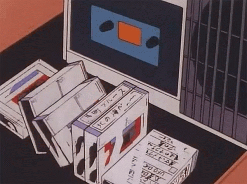 A Bunch Of Tapes Are Sitting On A Table Next To A Cassette Tape Player . GIF