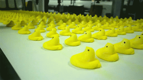 A Bunch Of Yellow Rubber Ducks Are Lined Up On A Conveyor Belt GIF