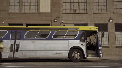 A Bus With The Number 0310 On The Front Is Parked In Front Of A Brick Building GIF