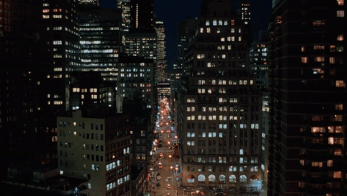A Busy City Street At Night With A Lot Of Buildings GIF
