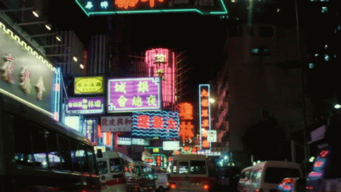 A Busy Street At Night With A Neon Sign That Says ' A ' On It GIF