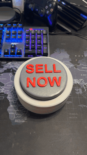 A Button That Says Sell Now Is On A Desk GIF