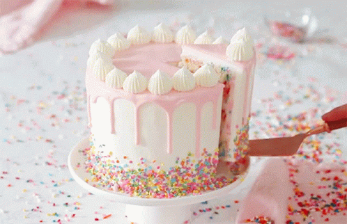 A Cake With Pink Frosting And Sprinkles Is Being Sliced GIF