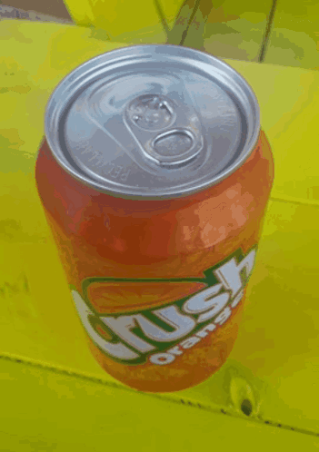 A Can Of Crush Orange Soda Is Sitting On A Yellow Table GIF