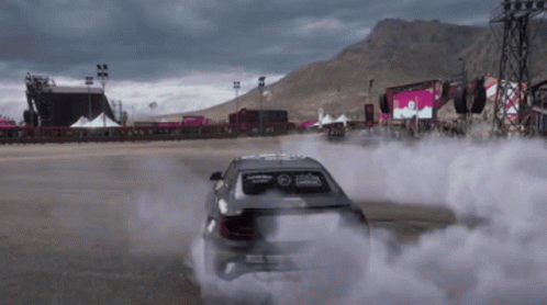 A Car Is Drifting On A Race Track With Smoke Coming Out Of It GIF