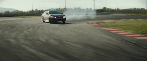A Car Is Drifting On A Track And Smoke Is Coming Out Of The Tires GIF