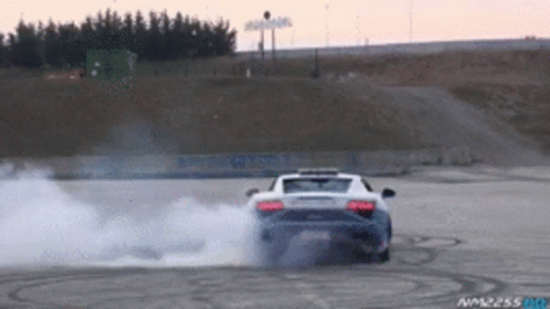 A Car Is Drifting On A Track With Smoke Coming Out Of The Exhaust Pipe GIF