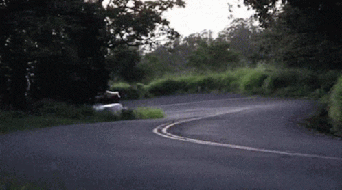 A Car Is Driving Down A Curvy Road In The Countryside GIF