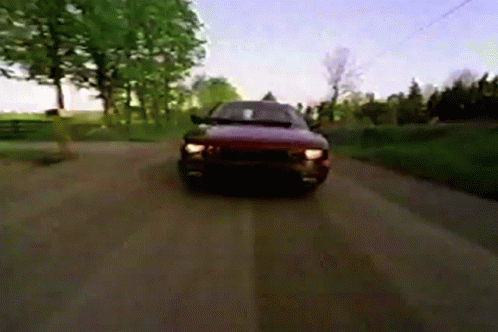 A Car Is Driving Down A Dirt Road In The Countryside GIF