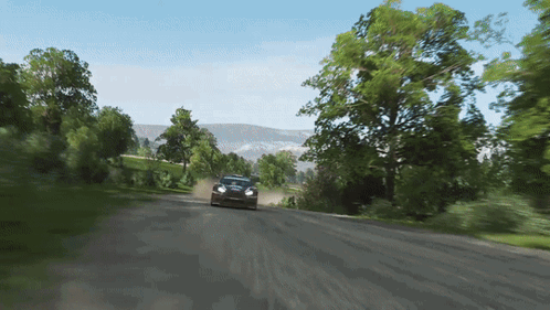 A Car Is Driving Down A Dirt Road With Trees On The Side GIF