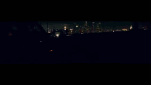 A Car Is Driving Down A Highway At Night With A Reflection Of A Building In The Background GIF