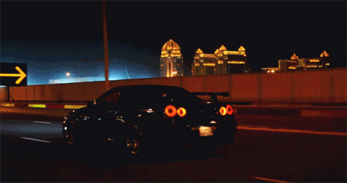 A Car Is Driving Down A Highway At Night With A Sign Behind It That Says ' Khara ' GIF
