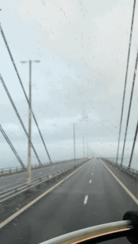 A Car Is Driving Down A Highway With A Gray Sky In The Background GIF
