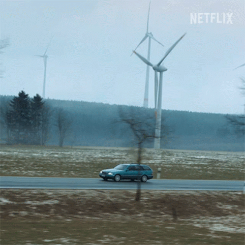 A Car Is Driving Down A Road With Windmills In The Background And A Netflix Logo GIF