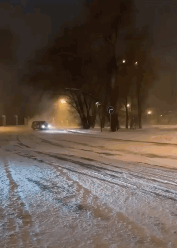 A Car Is Driving Down A Snow Covered Street GIF