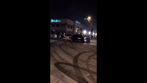 A Car Is Driving Down A Snowy Road At Night GIF