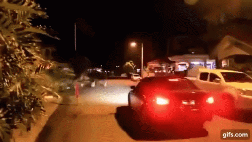 A Car Is Driving Down A Street At Night With A Red Tail Light GIF