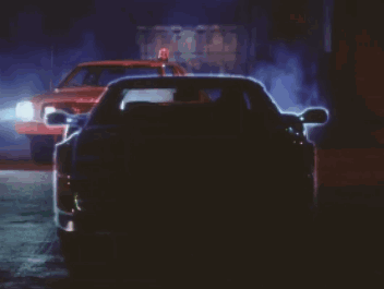A Car Is Driving Down A Street At Night With The Lights On GIF