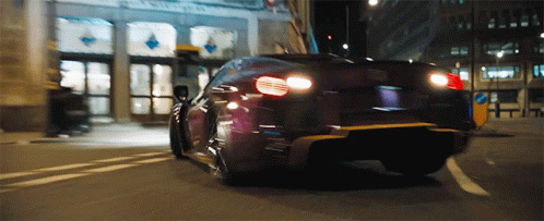 A Car Is Driving Down A Street With A Building In The Background That Has A Sign That Says No Parking GIF
