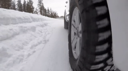A Car Is Driving On A Snow Covered Road GIF