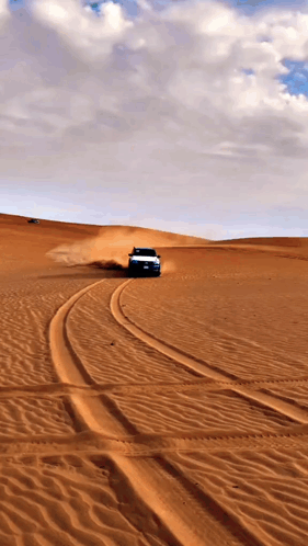 A Car Is Driving Through A Desert With A Cloudy Sky In The Background GIF