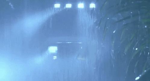 a car is driving through the rain in the dark .
