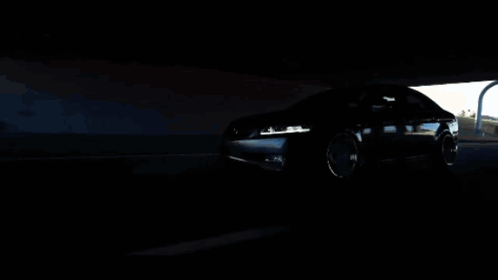 A Car Is Driving Under A Bridge In The Dark GIF