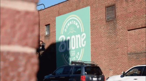 A Car Is Parked In Front Of A Building That Says Boone GIF