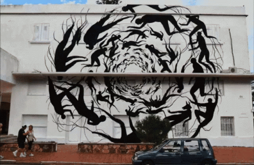 A Car Is Parked In Front Of A Building With A Large Painting On It GIF
