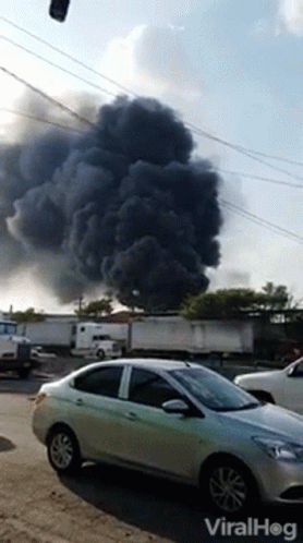 A Car Is Parked In Front Of A Large Cloud Of Smoke And The Words Viralhog Are On The Bottom Of The Screen GIF