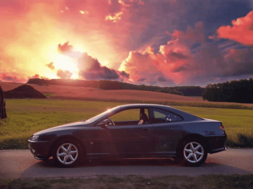 A Car Is Parked On The Side Of A Road In Front Of A Sunset GIF