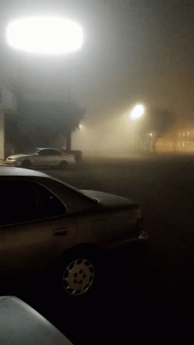 A Car Parked In A Foggy Parking Lot At Night GIF