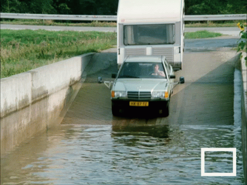 a car with a license plate that says ' hk-973-tf ' is driving through a flooded road