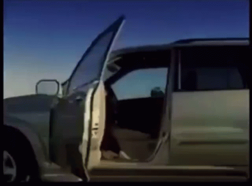 A Car With Its Doors Open Is Parked On A Dirt Road GIF