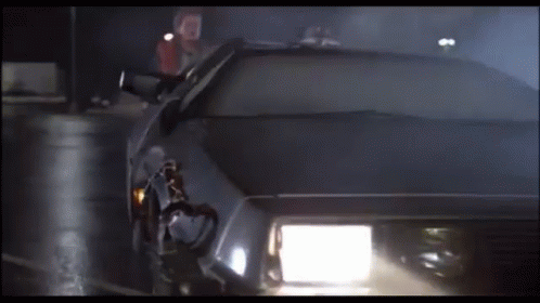 A Car With The Headlights On Is Driving Down A Dark Street GIF
