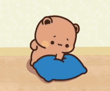 A Cartoon Bear Is Sitting On A Blue Pillow On A Wooden Floor . GIF