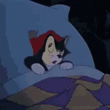 A Cartoon Cat Is Laying In A Bed With A Pillow . GIF
