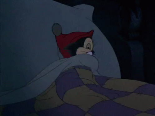 A Cartoon Cat Wearing A Red Hat Is Laying On A Bed GIF