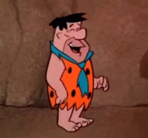 A Cartoon Character From The Flintstones Is Standing In Front Of A Rock Wall . GIF