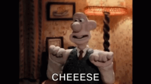A Cartoon Character In A Suit And Tie Is Pointing At The Camera And Saying Cheese . GIF