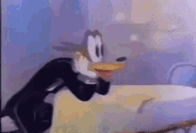 A Cartoon Character In A Tuxedo Is Standing In Front Of A Bed . GIF