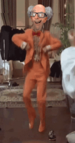A Cartoon Character In An Orange Suit Is Dancing In A Room GIF